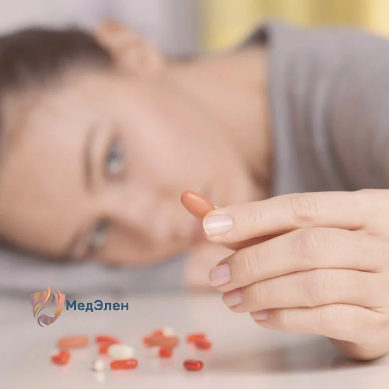 Девушка смотрит на таблетку в руке